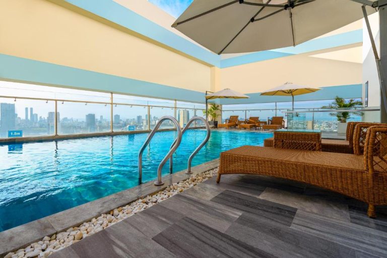 Piscina rooftop con vistas a la ciudad en G8 Luxury Hotel Da Nang con tumbonas y sombrillas