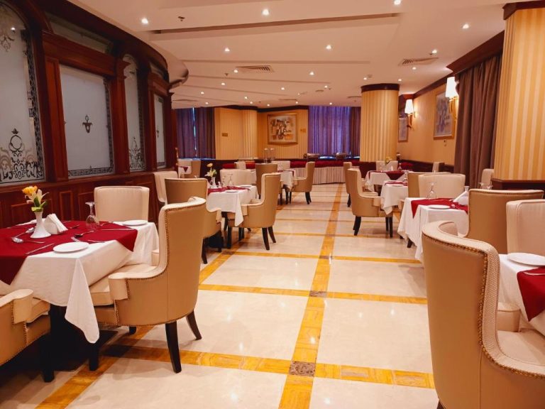 Elegante salón comedor del Royal Qatar Hotel con mesas vestidas en blanco y rojo y sillas tapizadas