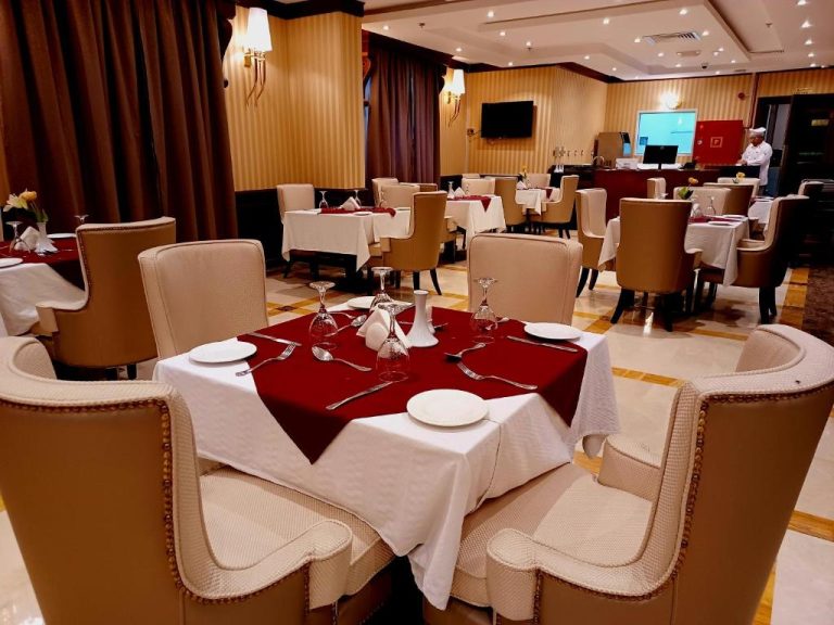 Restaurante elegante del Royal Qatar Hotel con mesas vestidas en rojo y blanco y vajilla fina