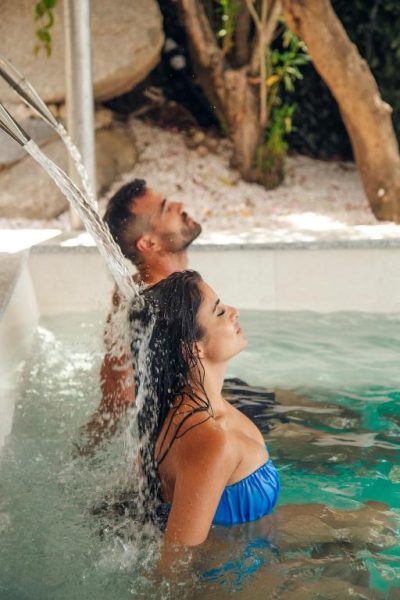 Pareja relajándose bajo una cascada de agua en el spa exterior del Hotel La Bitta Bovis Hotels