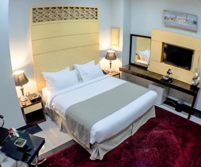 Habitación doble de lujo con cama king size y televisión en Doha Dynasty Hotel