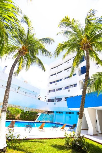 Piscina exterior con palmeras tropicales y tumbonas del Hotel Caribe Internacional Cancún