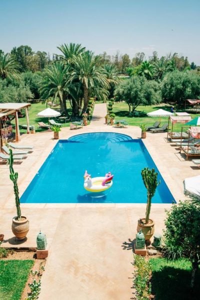 Piscina exterior con flotador unicornio y jardín de palmeras en La Villa Des Golfs & PinkCactus
