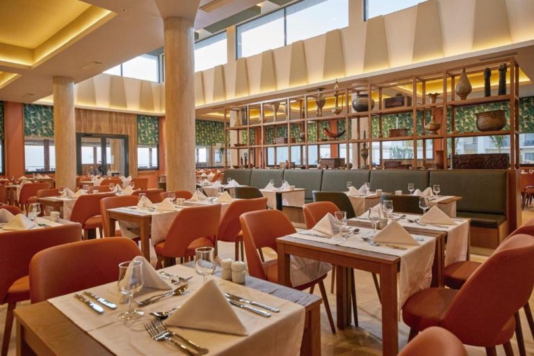 Restaurante principal con mesas elegantes y sillas naranjas del Hotel Riu Jambo All Inclusive en Zanzíbar