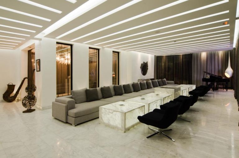 Amplio salón lobby del Cesar Resort & Spa con sofás grises, mesas de mármol y sillones negros de diseño