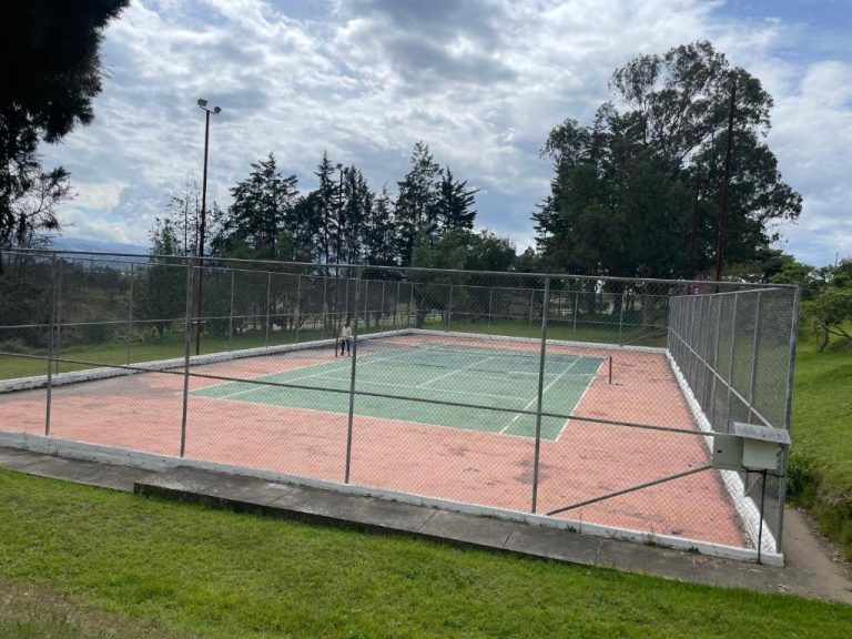 Cancha de tenis al aire libre con superficie roja y verde en Quito Airport Suites Hotel