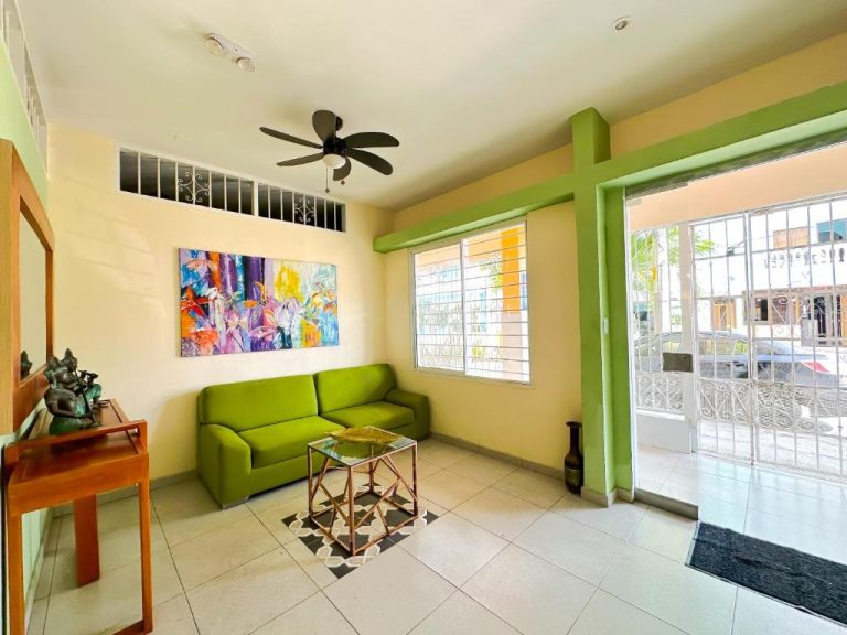 Sala de estar con sofá verde y arte colorido en Hotel Zamay Centro Histórico