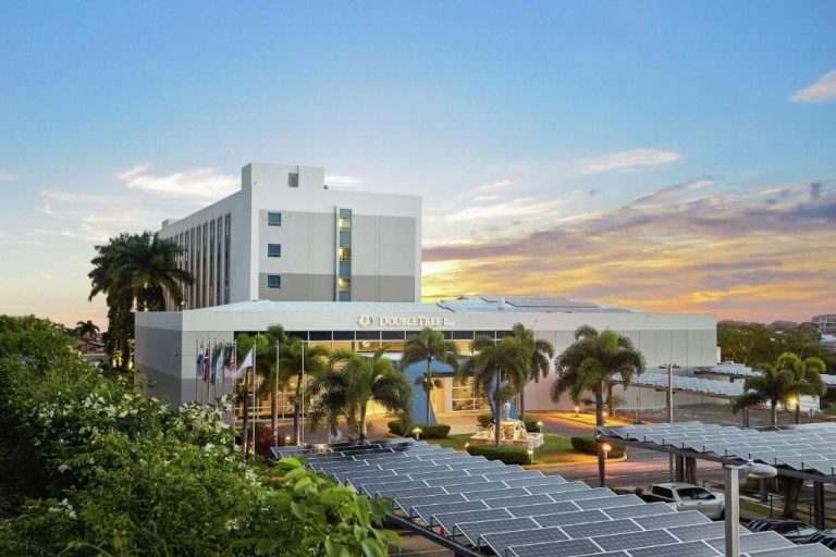 Vista exterior del DoubleTree by Hilton Managua con paneles solares y palmeras al atardecer