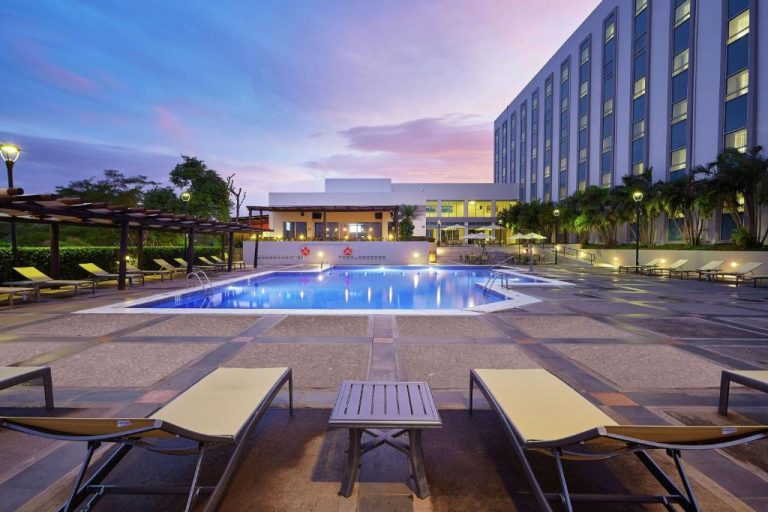 Piscina exterior iluminada al atardecer del DoubleTree by Hilton Managua con tumbonas y jardines