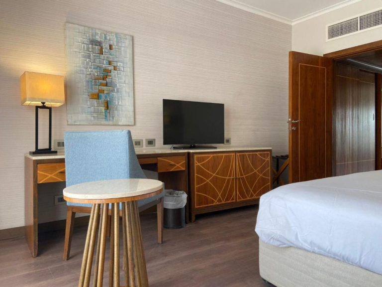 Habitación con escritorio de madera, televisión y cama doble en Hotel Studio