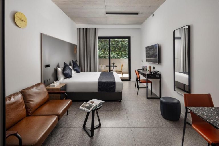 Suite moderna con cama doble, sofá de cuero y escritorio en Grands Suites Hotel and Spa Sliema