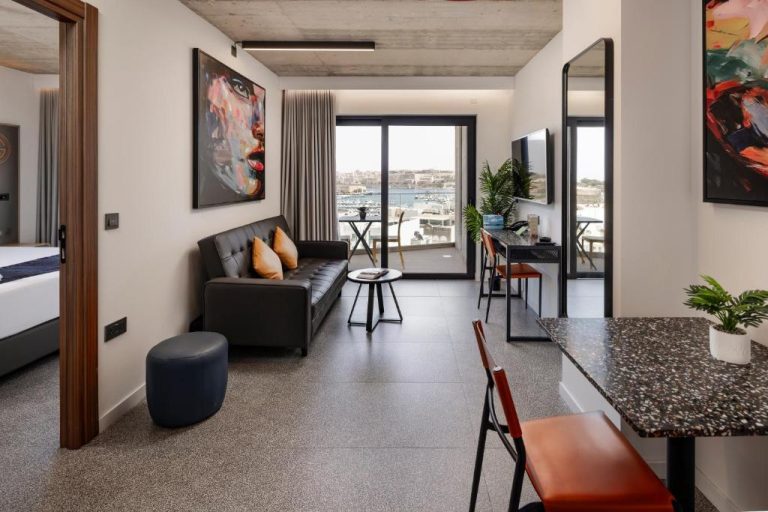 Suite moderna con salón, sofá de cuero y vistas al puerto marítimo en Grands Suites Hotel and Spa Sliema