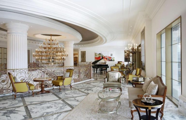 Lujoso lobby del Al Habtoor Palace con araña de cristal dorada, piano de cola y elegante mobiliario clásico