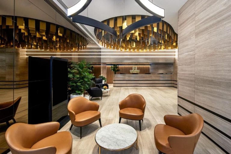 Elegante lobby con sillones de cuero y recepción del Meriton Suites Pitt Street en Sídney