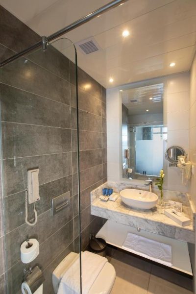 Baño moderno con ducha de cristal y lavabo sobre encimera de mármol en Naama Bay Suites & SPA