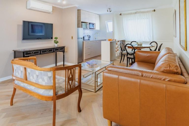 Salón con sofá de cuero y cocina americana integrada en los apartamentos Orly Suites