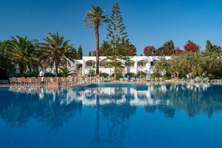 Gran piscina exterior con tumbonas y palmeras del Le Hammamet Hôtel & Spa en Túnez