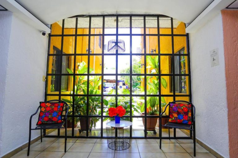 Lobby del Hotel Hacienda Cancun con ventanal de hierro forjado, sillas típicas y plantas tropicales