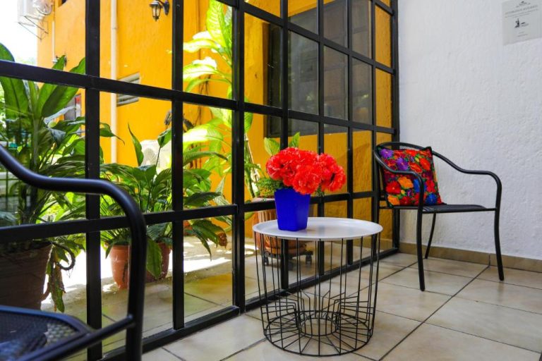 Terraza interior con sillas, mesa decorativa y flores rojas del Hotel Hacienda Cancun