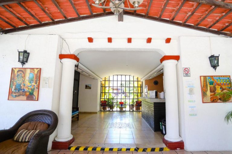Lobby y recepción colonial con columnas blancas y techo de madera del Hotel Hacienda Cancun