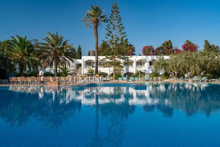 Amplia piscina exterior con tumbonas y palmeras del Le Hammamet Hôtel & Spa en Túnez