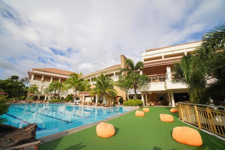 Piscina exterior con área de descanso y tumbonas del Timberland Highlands Resort rodeado de palmeras