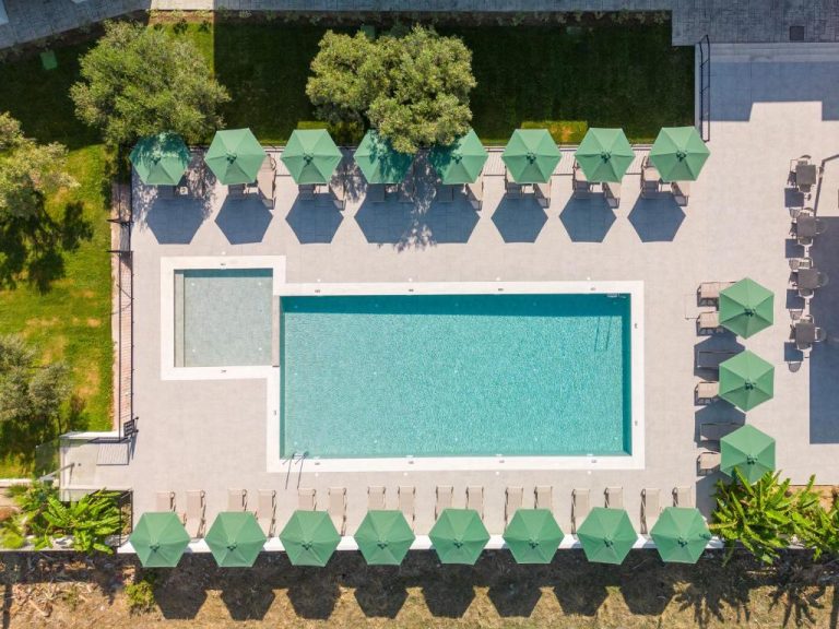 Vista aérea de la piscina exterior con tumbonas y sombrillas verdes del Smaragdi Kos Hotel