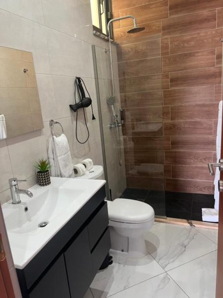 Baño moderno con ducha de lluvia y revestimiento de madera en Residencial Santo Amaro