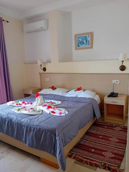 Habitación doble con cama decorada con flores y toallas en el Hôtel Romane