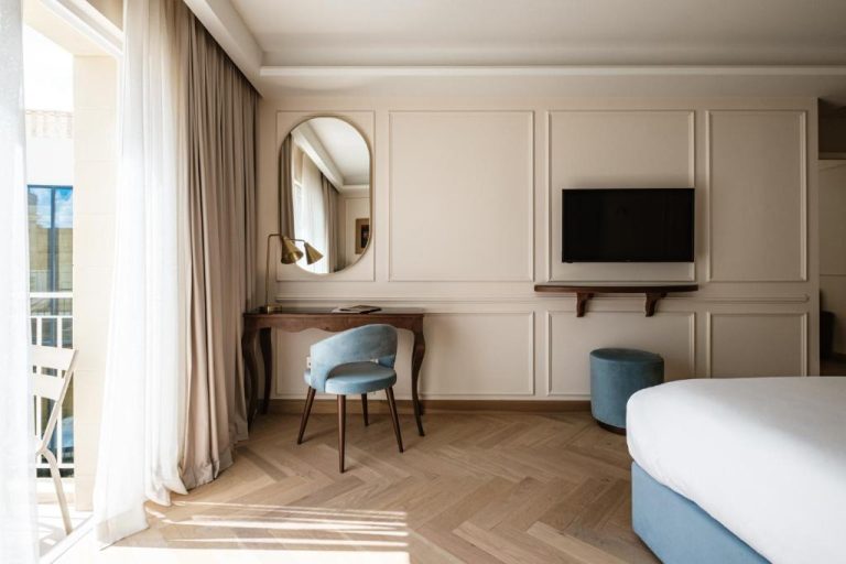 Habitación elegante con escritorio de madera y espejo ovalado en Palazzo Castagna Boutique Hotel