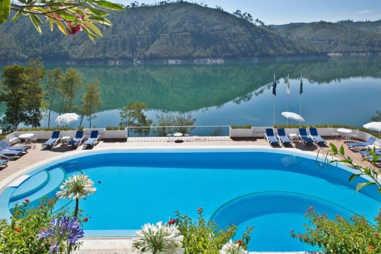 Piscina exterior con vistas al lago y montañas del Lago Azul Eco Hotel rodeada de tumbonas