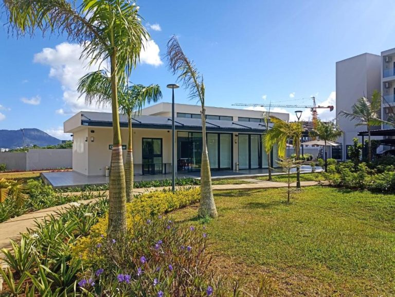 Jardín tropical con palmeras y edificio moderno del Royal Green Wellness Resort con montañas al fondo