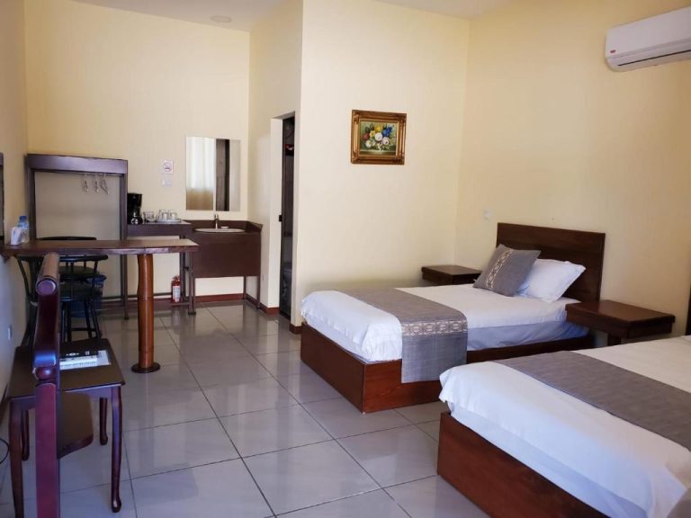 Habitación twin con dos camas individuales, escritorio y aire acondicionado en Villa Garita Inn