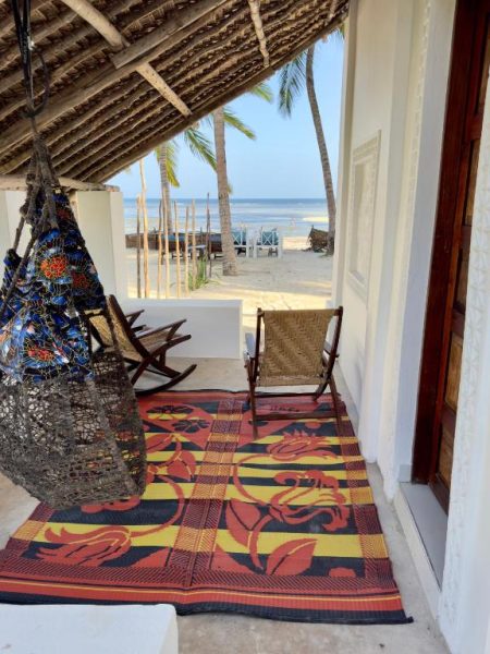 Terraza con hamaca y sillas frente a la playa de palmeras en Sawa Sawa Beach House