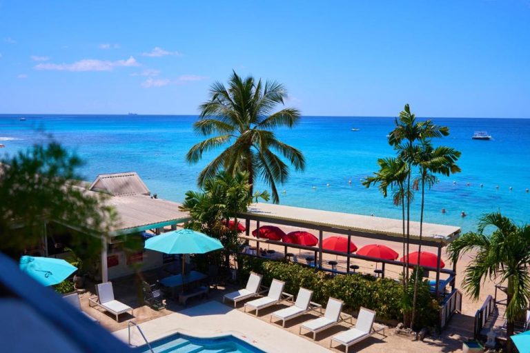 Piscina exterior con tumbonas y vistas al mar turquesa en Tropical Sunset Beach Apartment Hotel
