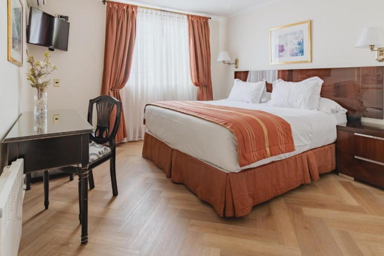 Habitación doble con cama matrimonial y suelo de madera en el hotel Orly Suites