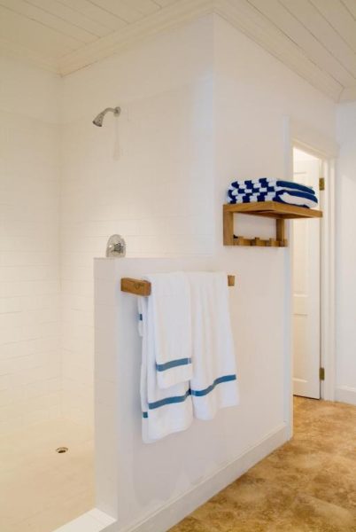 Baño con ducha abierta y toallas blancas con franja azul en The Atlantis Historic Inn