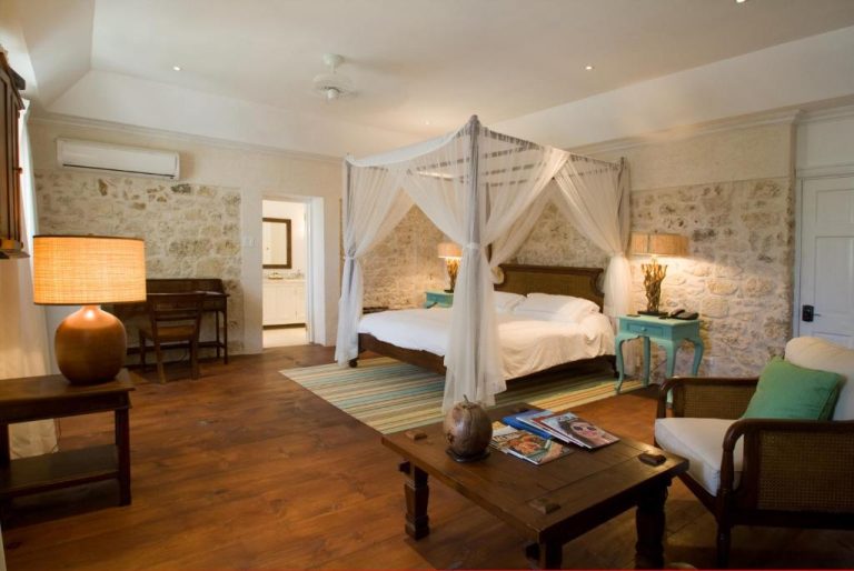 Habitación con cama de dosel y paredes de piedra en The Atlantis Historic Inn