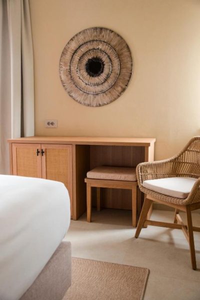 Escritorio de madera con silla de rattan y decoración artesanal en habitación del Mangia's Brucoli Sicily