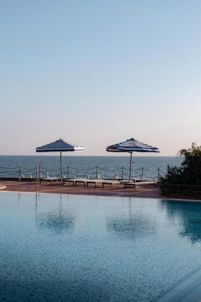 Piscina infinita con tumbonas y sombrillas frente al mar en Mangia's Brucoli Sicily Autograph Collection