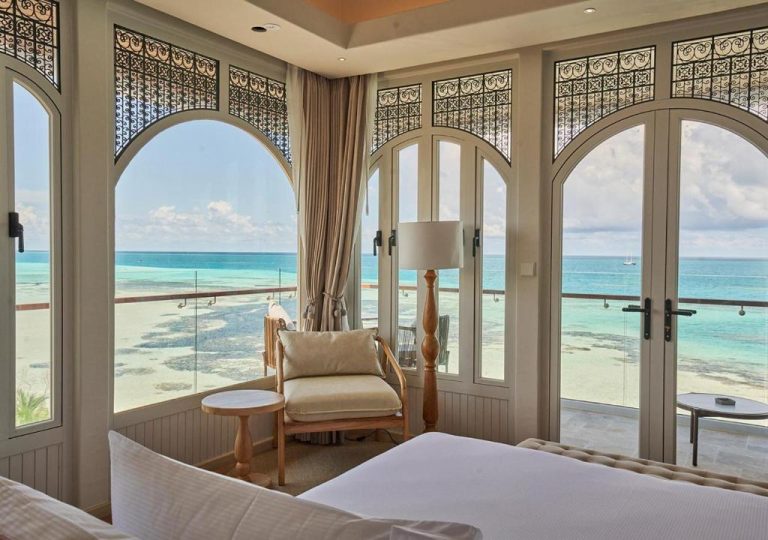 Habitación de lujo con ventanales arqueados y vistas al océano turquesa en Stone Hotel Dhiffushi Maldivas