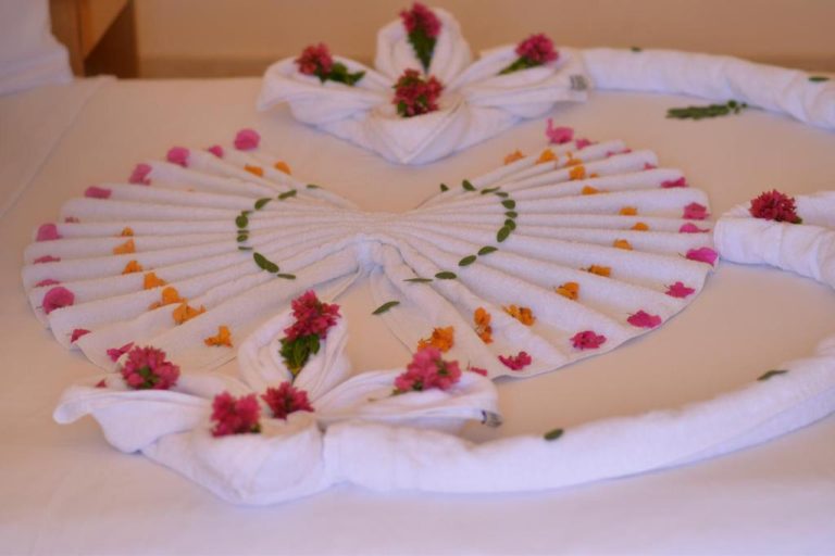 Decoración artística de toallas blancas con flores en la cama del Sharm Cliff Hotel