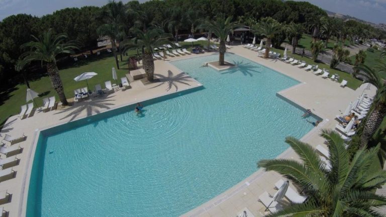 Vista aérea de la gran piscina exterior con tumbonas y palmeras del Eureka Palace Hotel Spa Resort