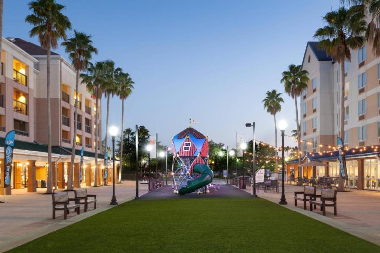 Área de juegos infantiles exterior del SpringHill Suites Orlando Lake Buena Vista al atardecer con palmeras