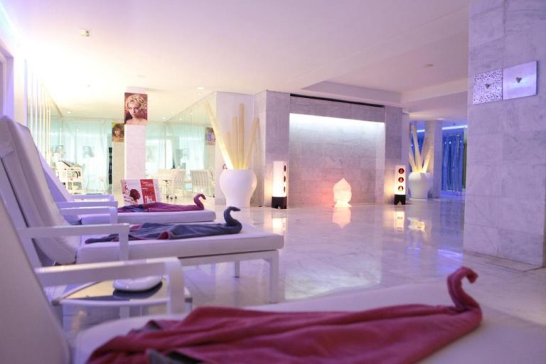 Zona de relax con tumbonas blancas y ambiente iluminado en el spa del Cesar Resort & Spa