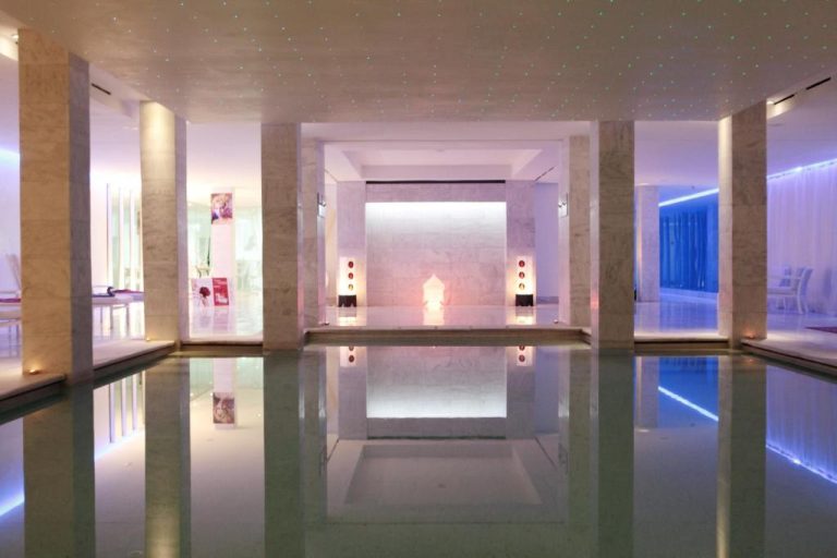 Piscina interior con iluminación ambiental y zona spa del Cesar Resort & Spa