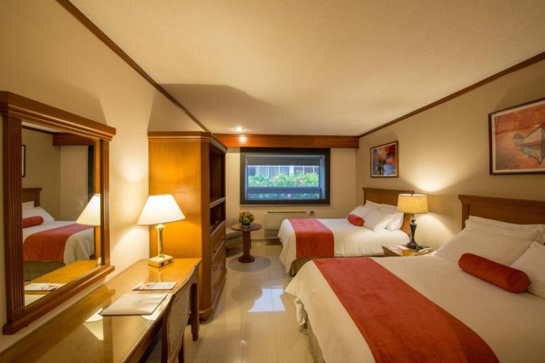Habitación doble con dos camas y decoración en tonos rojos del Hotel Globales Camino Real Managua