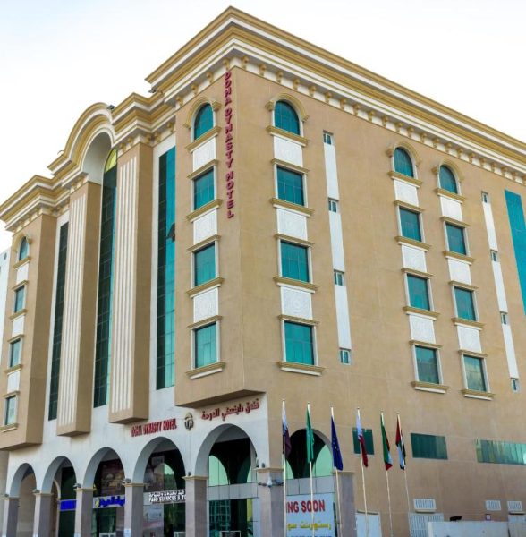 Fachada exterior del Doha Dynasty Hotel con arquitectura clásica y banderas internacionales en Qatar