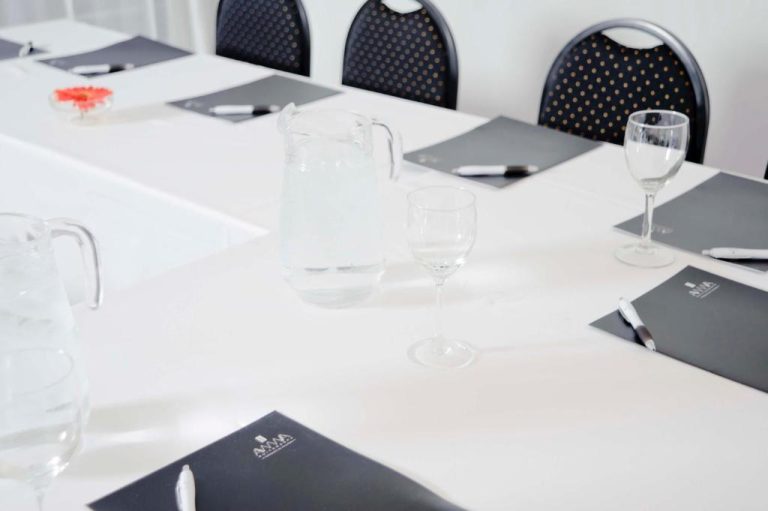 Sala de reuniones con mesas y sillas elegantes en Awwa Suites & Spa, equipada con material de conferencias
