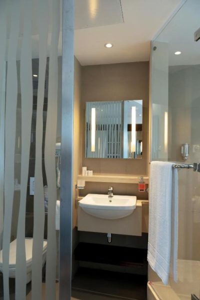 Baño moderno con lavabo empotrado y espejo iluminado en el Hotel Voila Bagatelle